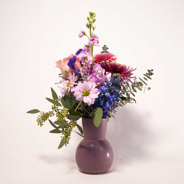 Vase arrangement in monochromatic blend of pink and purple blooms. 