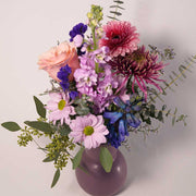 Vase arrangement in monochromatic blend of pink and purple blooms. 