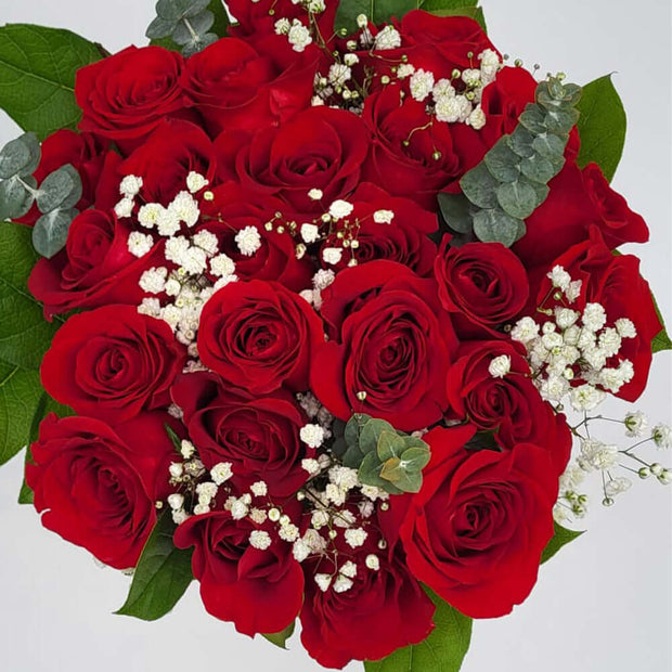 Two dozen imported, long-stemmed red roses nestled amidst seasonal greenery and elegant filler flowers.
