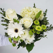 White flowers like rose, gerbera, hydrangea, lily and mums are accented with green flowers and seasonal greenery.