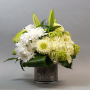 Classic white and green blooms arranged in a clear round vase. Classic flowers like lily and hydrangea make this arrangement  nice and elegant.