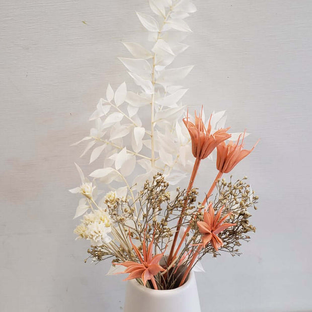 Small flowers in white and coral combination arranged in a low white vase.