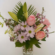 Filled with delicately coloured pink or mauve roses and a lily, this soft-toned vase overflows with sweetness and charm.
