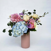 Pink tall vase filled with soft coloured flowers