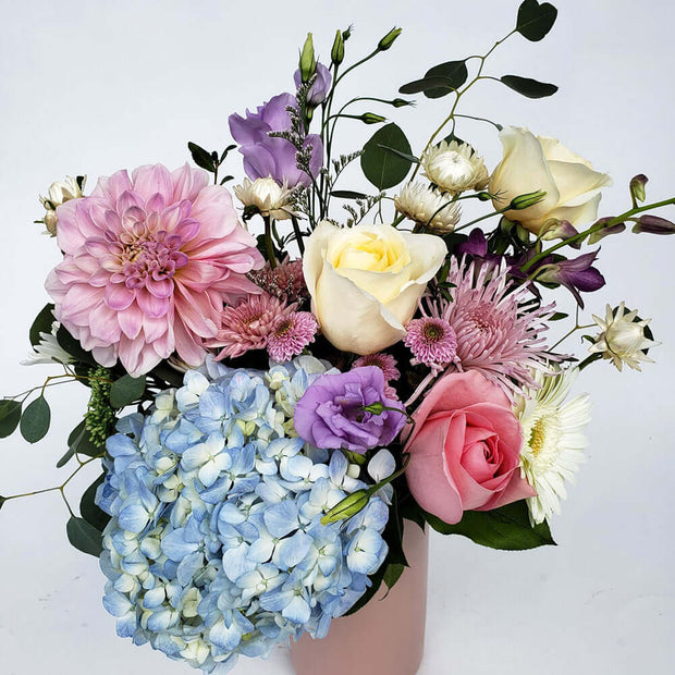 Pink tall vase filled with soft coloured flowers