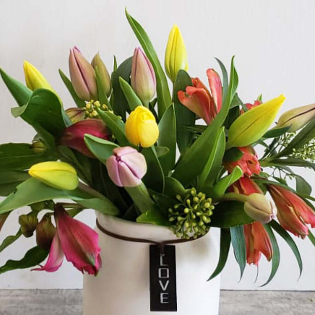 Colourful tulips with alstroemeria in a ceramic vase.